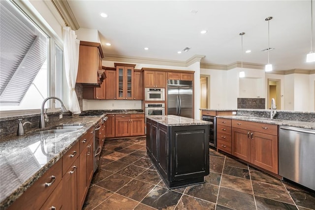 kitchen featuring sink, light stone counters, pendant lighting, a kitchen island, and appliances with stainless steel finishes