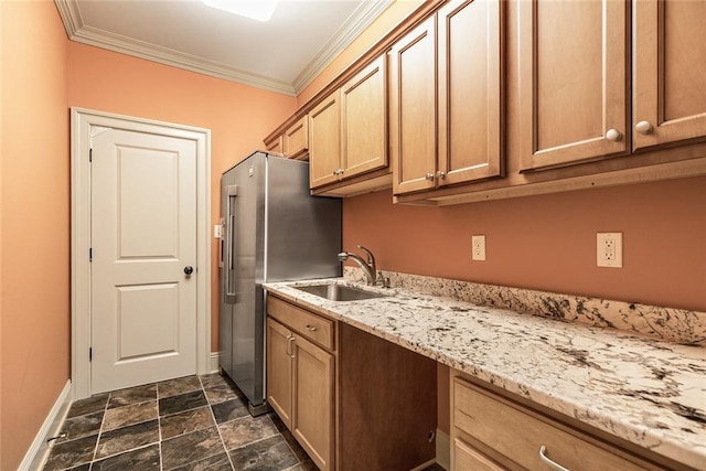 kitchen featuring high end fridge, light stone countertops, ornamental molding, and sink