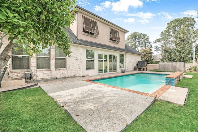 back of house featuring a fenced in pool, a patio area, and a lawn