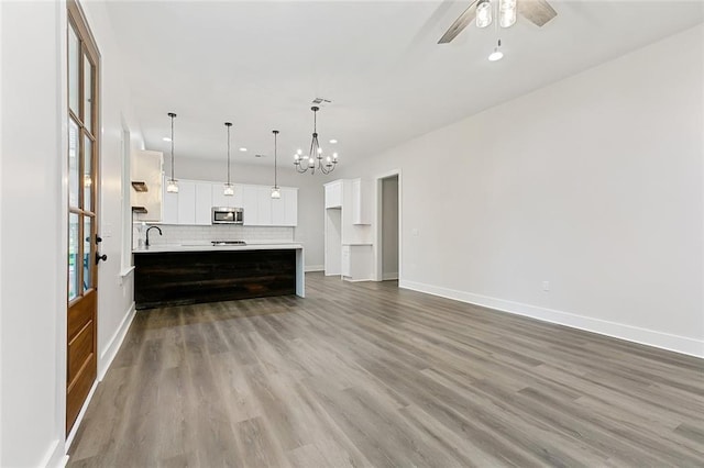 unfurnished living room featuring sink, ceiling fan with notable chandelier, and light wood-type flooring