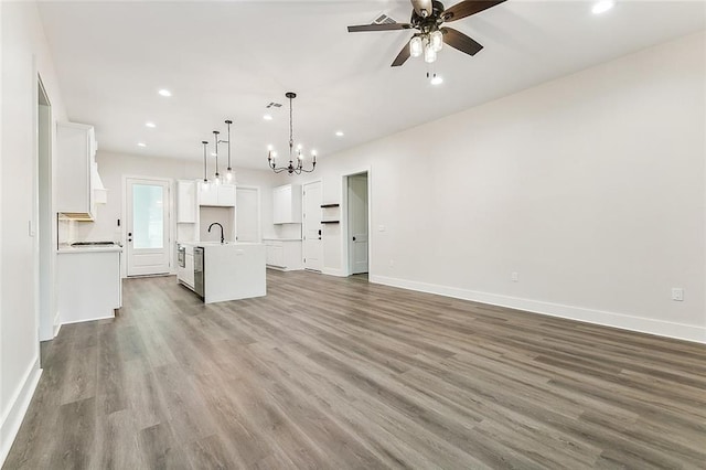 unfurnished living room with hardwood / wood-style floors, sink, and ceiling fan with notable chandelier