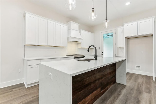 kitchen featuring a kitchen island with sink, hanging light fixtures, and sink