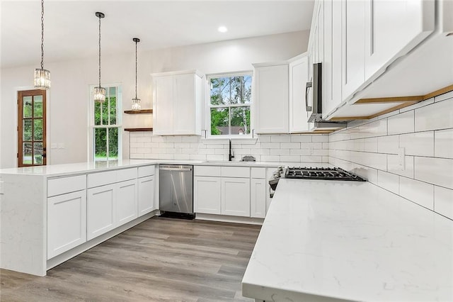 kitchen with stainless steel appliances, light stone countertops, sink, and white cabinets