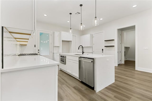 kitchen with pendant lighting, sink, light hardwood / wood-style flooring, appliances with stainless steel finishes, and white cabinetry