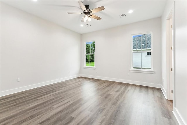 empty room with dark hardwood / wood-style flooring, ceiling fan, and a healthy amount of sunlight