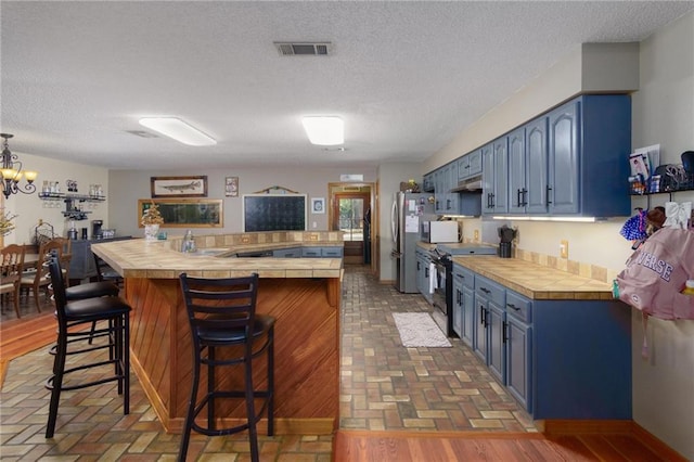 kitchen with blue cabinetry, a textured ceiling, and stainless steel appliances