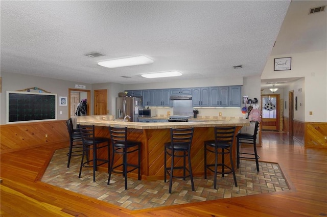 kitchen featuring a breakfast bar, a textured ceiling, hardwood / wood-style flooring, and stainless steel appliances