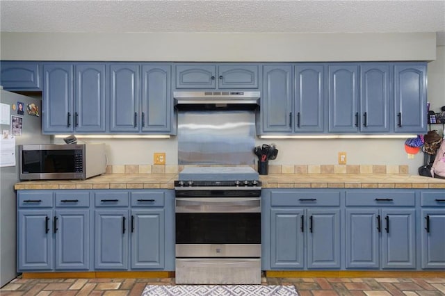 kitchen featuring blue cabinets, appliances with stainless steel finishes, and a textured ceiling