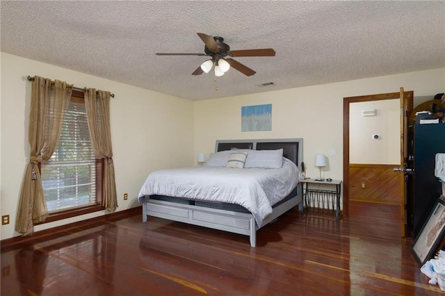 bedroom with wood walls, dark hardwood / wood-style floors, a textured ceiling, and ceiling fan