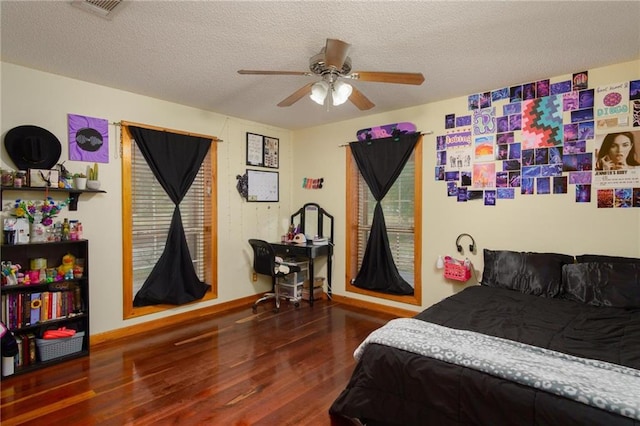 bedroom featuring dark wood-type flooring, a textured ceiling, and ceiling fan