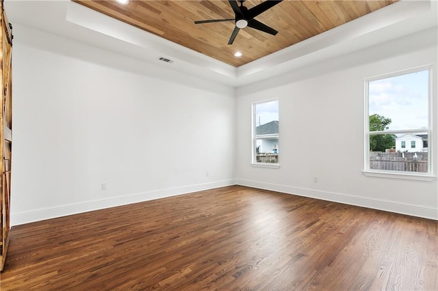 spare room featuring ceiling fan, a barn door, wooden ceiling, a tray ceiling, and dark hardwood / wood-style floors