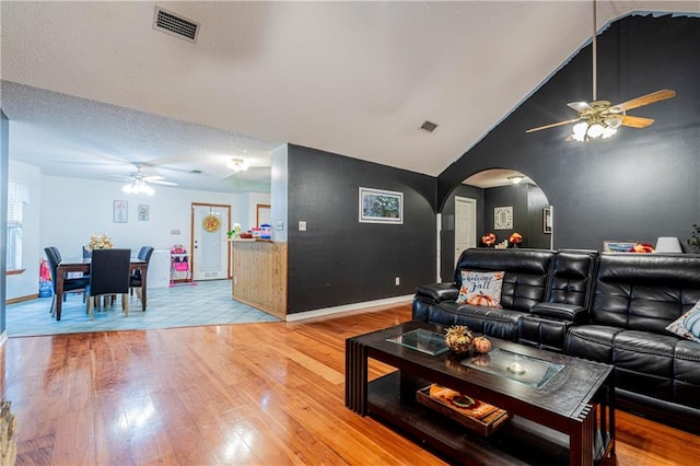 living room with ceiling fan, high vaulted ceiling, wood-type flooring, and a textured ceiling