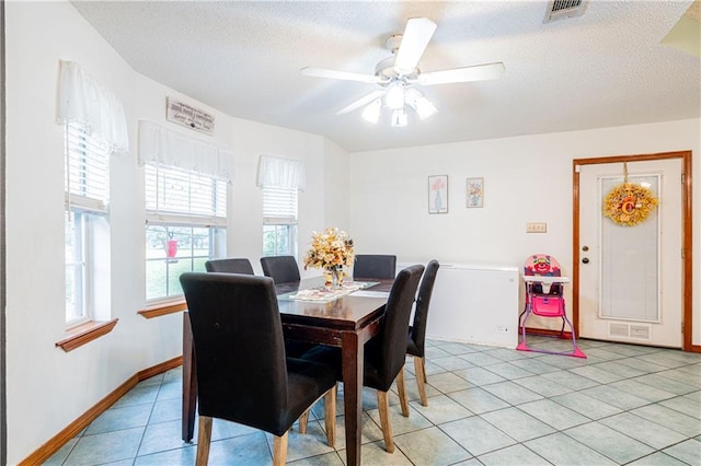 dining space with a textured ceiling, light tile patterned floors, and ceiling fan