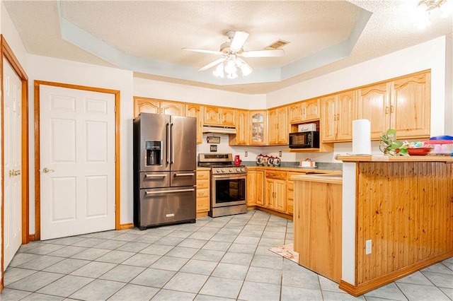 kitchen featuring kitchen peninsula, stainless steel appliances, a tray ceiling, a textured ceiling, and ceiling fan