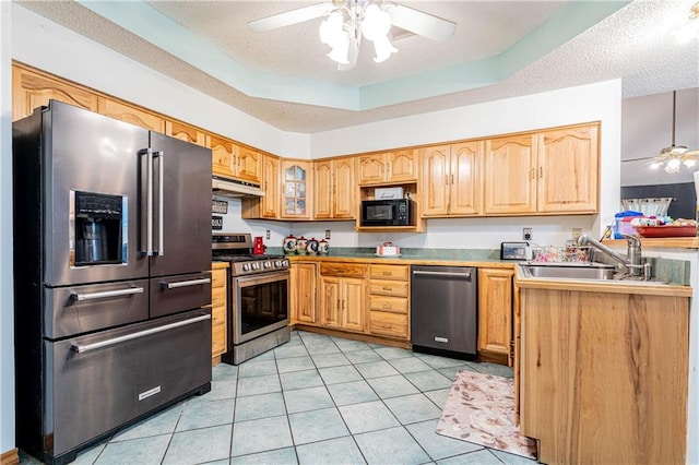 kitchen with light tile patterned floors, stainless steel appliances, a raised ceiling, a textured ceiling, and ceiling fan