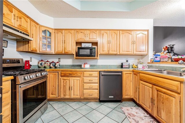 39523 E Porter River Rd, Pearl River, LA 70452 - kitchen featuring appliances with stainless steel finishes, under cabinet range hood, a textured ceiling, light tile patterned floors, and glass insert cabinets