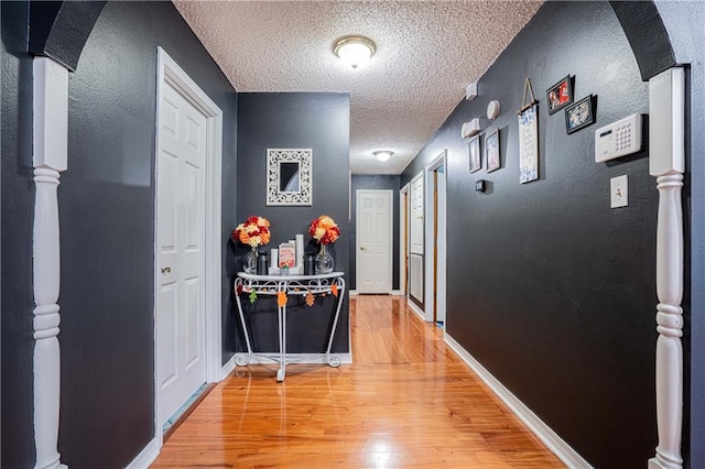 hall with hardwood / wood-style floors and a textured ceiling