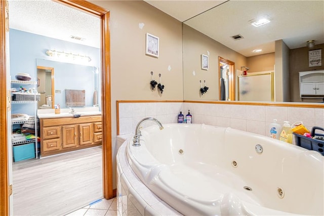 bathroom featuring vanity, a textured ceiling, independent shower and bath, and tile patterned floors