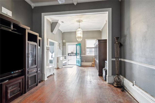 foyer entrance featuring a notable chandelier, ornamental molding, and hardwood / wood-style floors