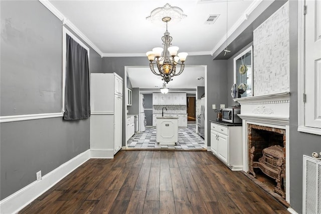 foyer entrance featuring dark hardwood / wood-style floors, sink, crown molding, a brick fireplace, and a chandelier