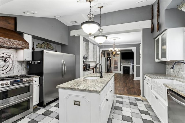 kitchen featuring white cabinets, appliances with stainless steel finishes, premium range hood, and a kitchen island with sink