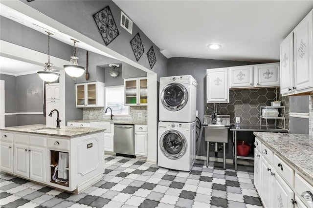 clothes washing area with stacked washing maching and dryer and sink