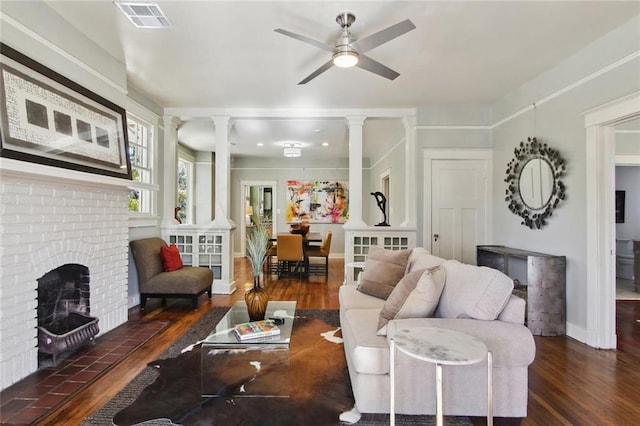 living room featuring a fireplace, dark hardwood / wood-style flooring, ceiling fan, and decorative columns