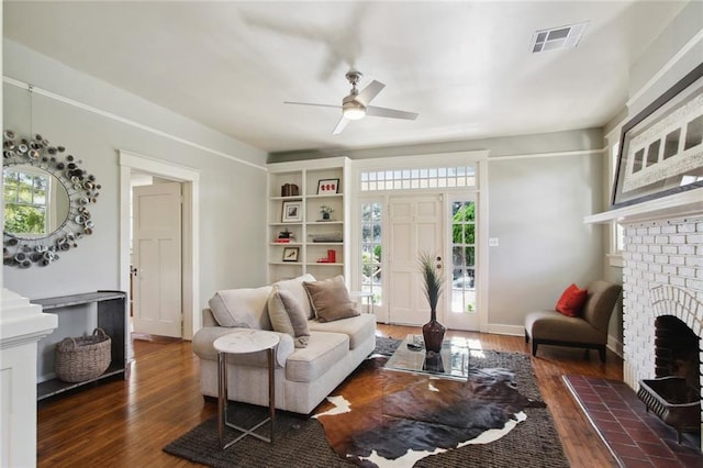 living room featuring a brick fireplace, dark wood-type flooring, and ceiling fan