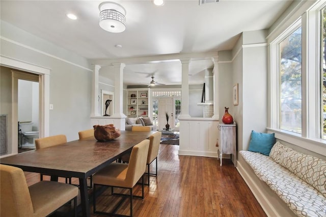 dining space with built in shelves, ceiling fan, dark hardwood / wood-style flooring, and decorative columns