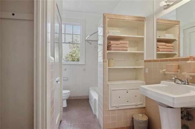 bathroom with washtub / shower combination, tile patterned flooring, toilet, and tile walls