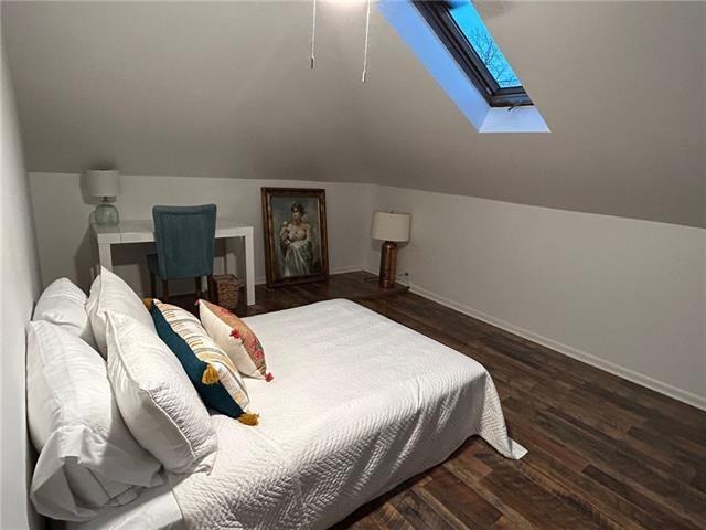 bedroom with dark wood-type flooring and vaulted ceiling with skylight