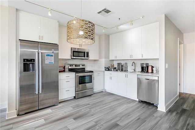 kitchen featuring sink, white cabinetry, appliances with stainless steel finishes, and decorative light fixtures