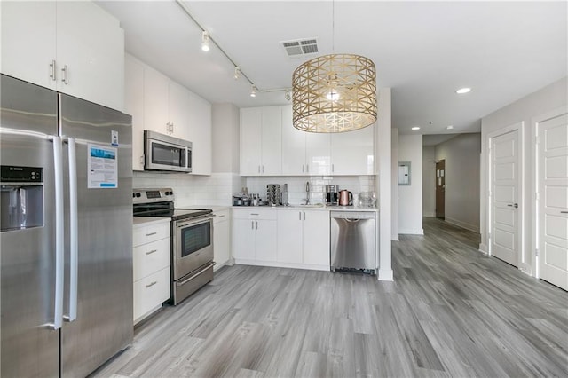 kitchen featuring stainless steel appliances, white cabinets, sink, light hardwood / wood-style flooring, and decorative light fixtures