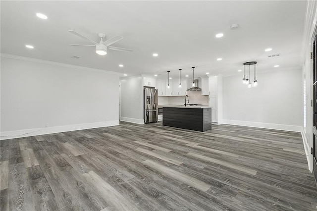 unfurnished living room featuring ornamental molding, sink, dark wood-type flooring, and ceiling fan