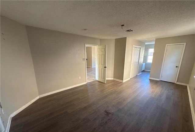 empty room with dark hardwood / wood-style floors and a textured ceiling