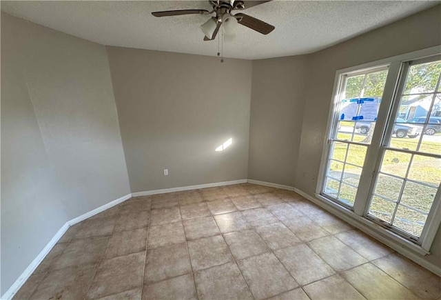 tiled spare room featuring a textured ceiling and ceiling fan