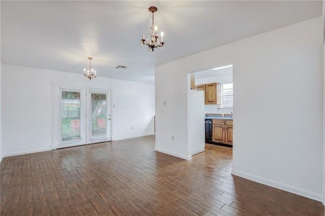 unfurnished living room featuring sink, a chandelier, and dark hardwood / wood-style floors