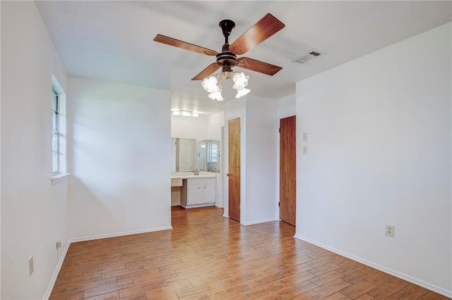 empty room featuring light wood-type flooring, ceiling fan, and sink