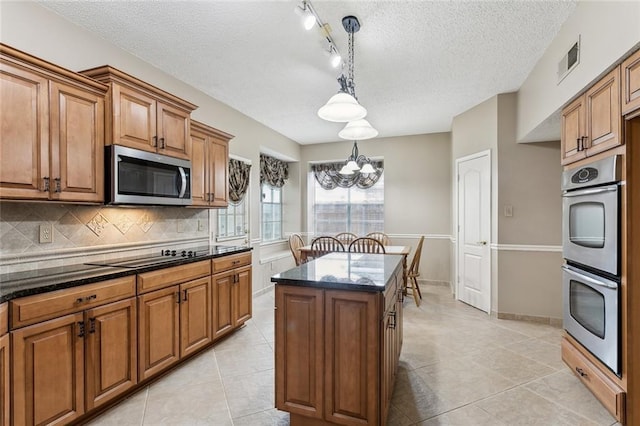 kitchen featuring a kitchen island, pendant lighting, light tile patterned floors, a chandelier, and appliances with stainless steel finishes