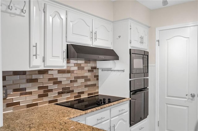 kitchen with black appliances, light stone counters, white cabinetry, and backsplash