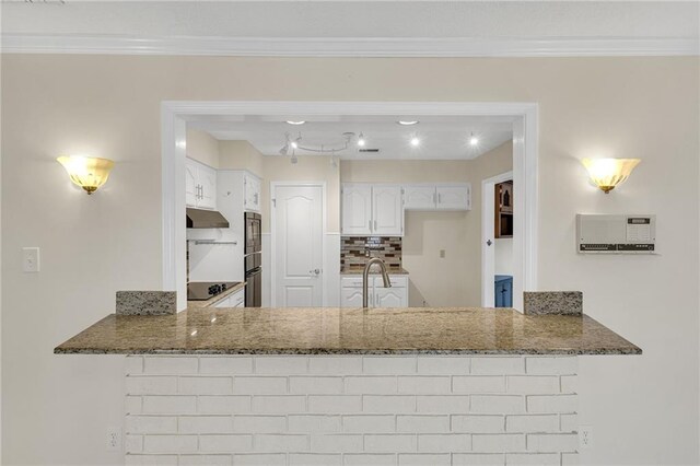 kitchen featuring white cabinetry, kitchen peninsula, sink, and dark stone counters