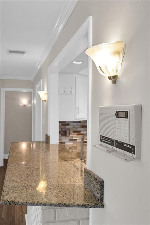 kitchen featuring dark wood-type flooring, stone countertops, white cabinetry, and ornamental molding