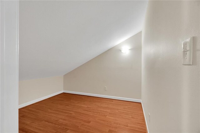 bonus room with hardwood / wood-style floors and vaulted ceiling