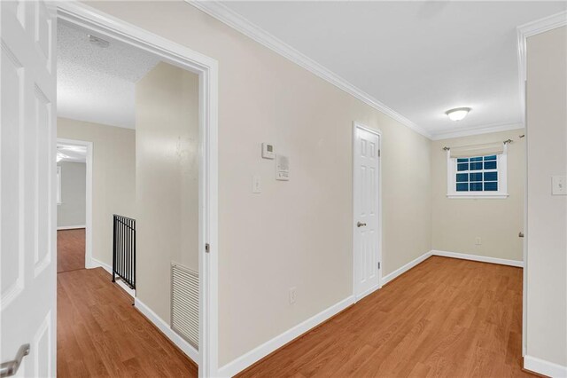 hall with light hardwood / wood-style floors and ornamental molding