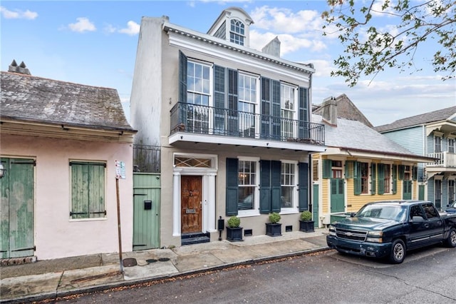 1216 Burgundy St, New Orleans, LA 70116 - view of front of house featuring a balcony, stucco siding, and a chimney