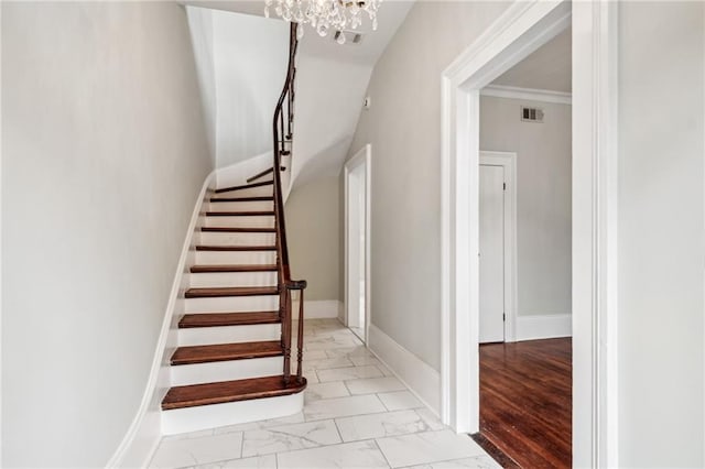 stairway featuring ornamental molding, hardwood / wood-style floors, and a chandelier