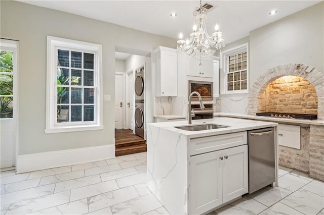 1216 Burgundy St, New Orleans, LA 70116 - kitchen featuring a sink, stacked washer and clothes dryer, light marble finish floors, stainless steel dishwasher, and light stone counters