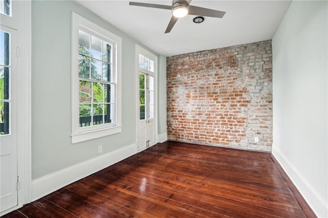 spare room featuring ceiling fan, brick wall, and dark hardwood / wood-style flooring