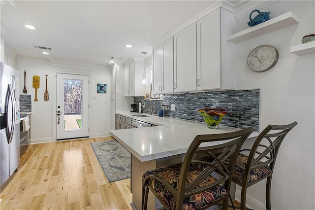 kitchen featuring sink, a breakfast bar, kitchen peninsula, light hardwood / wood-style flooring, and white cabinets