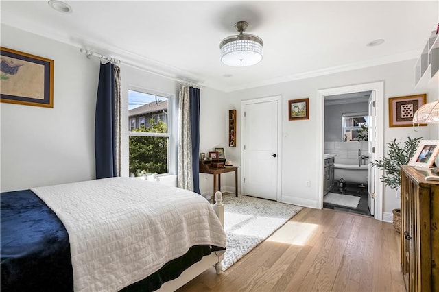 bedroom featuring ensuite bath, ornamental molding, and light hardwood / wood-style flooring